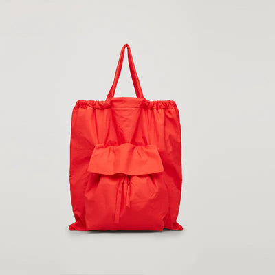 Red tote bag with ruffled pocket on a light gray background