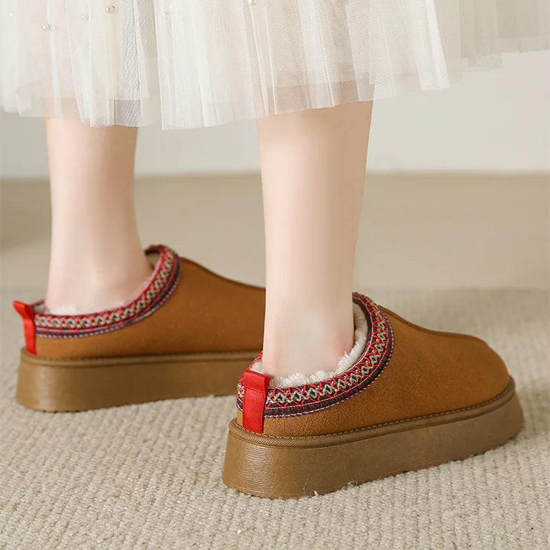 Brown slip-on shoes with red accents worn by a person on a carpeted floor.