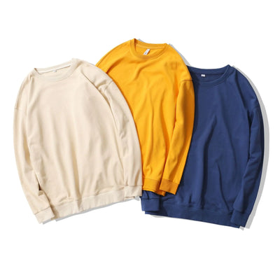 Three plain sweatshirts in beige, yellow, and blue on a white background