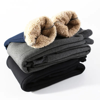 Stack of folded fleece pants in gray, black, and blue with fluffy brown trim on a white background