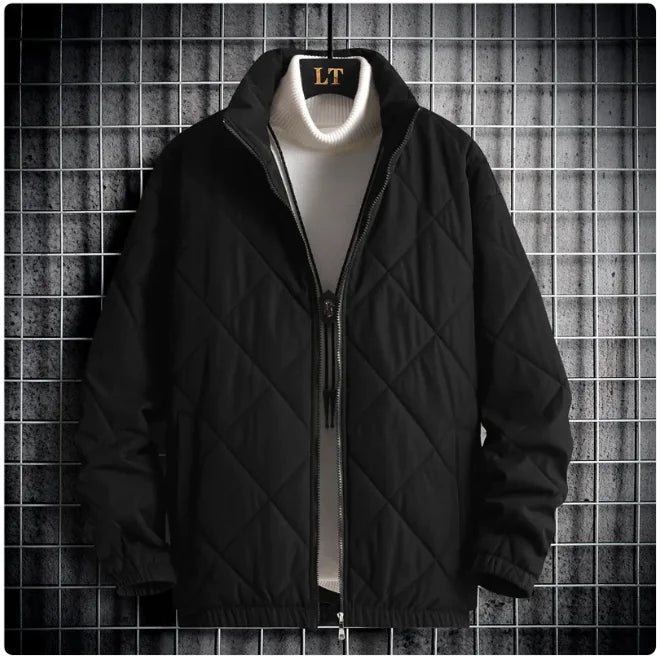 Black quilted jacket with a white shirt underneath on a textured gray background