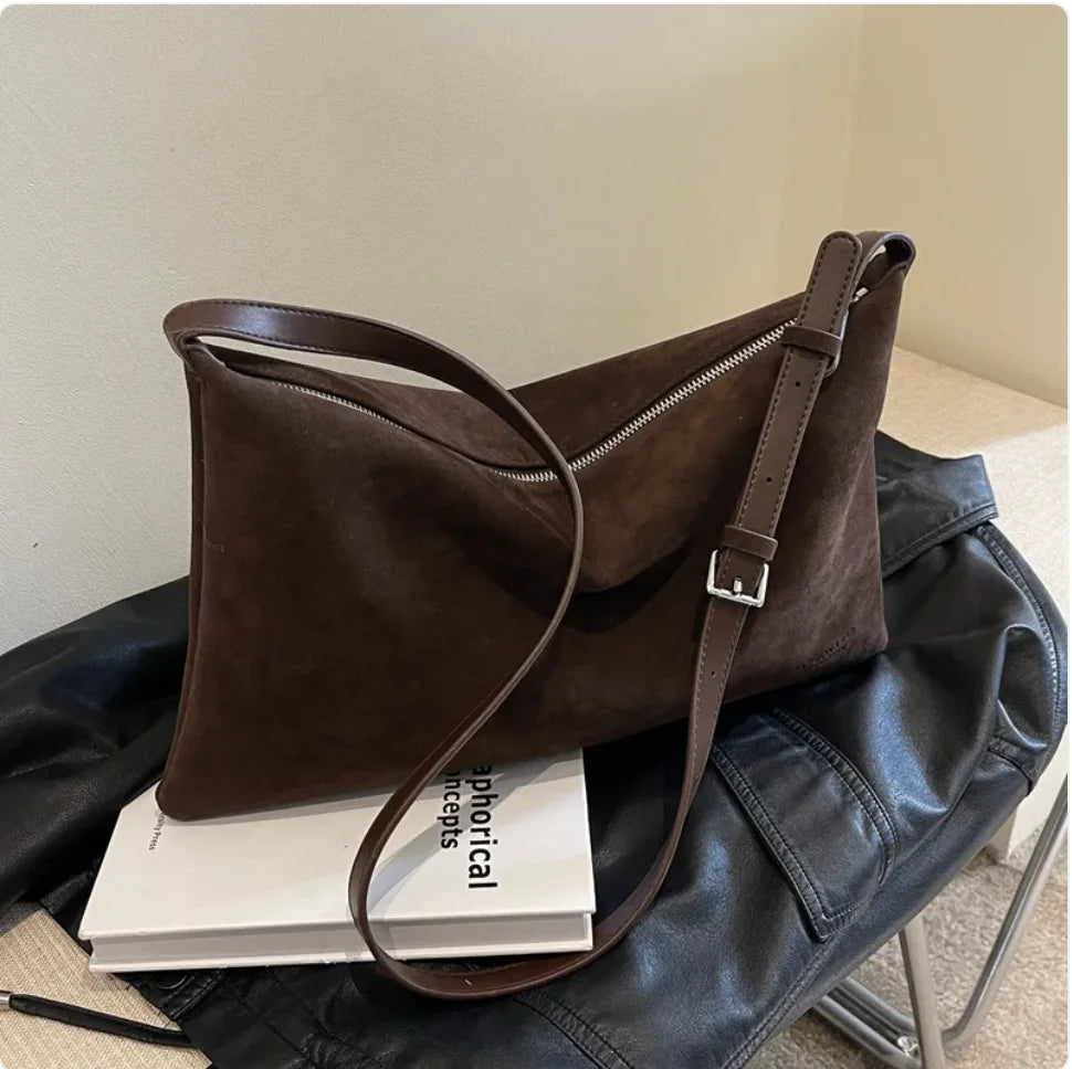 Brown leather handbag on a black jacket with a book underneath