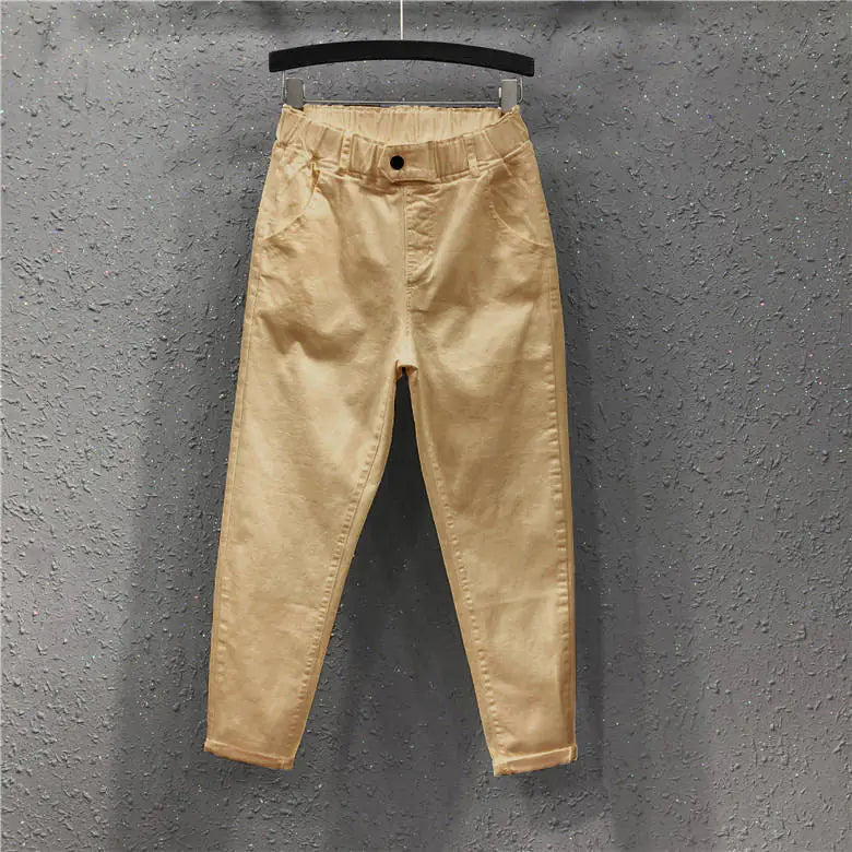 Beige pants hanging on a hanger against a gray textured wall