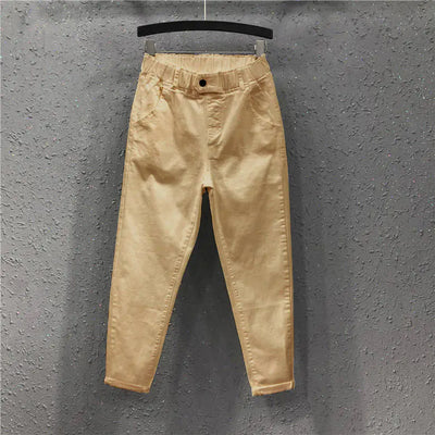 Beige pants hanging on a hanger against a gray textured wall