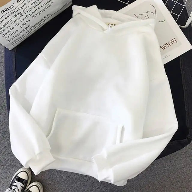 White hoodie on a dark surface with text and clothing items in the background