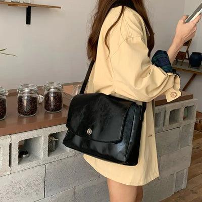 Person holding a black handbag in an indoor setting with jars on a counter.