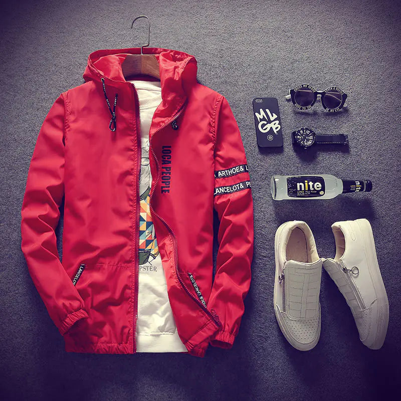 Red jacket, white sneakers, sunglasses, and other items on a gray surface