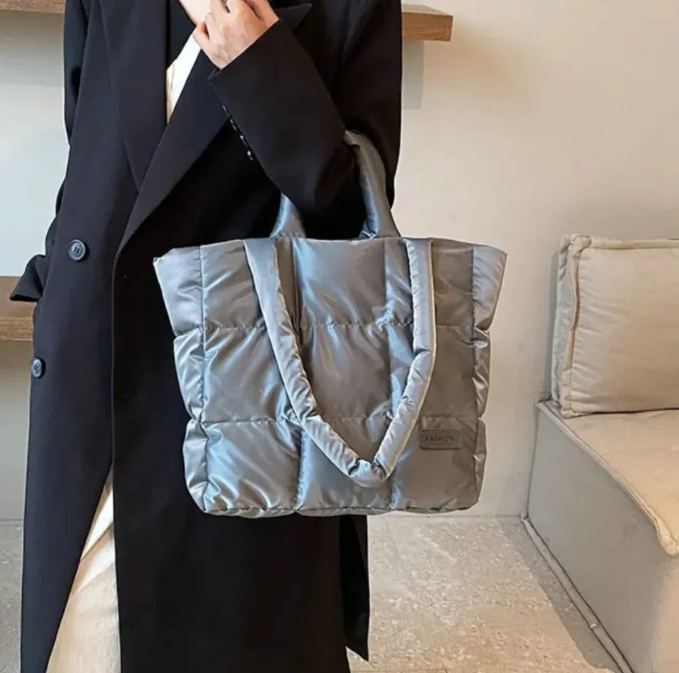 Person holding a gray puffer bag indoors