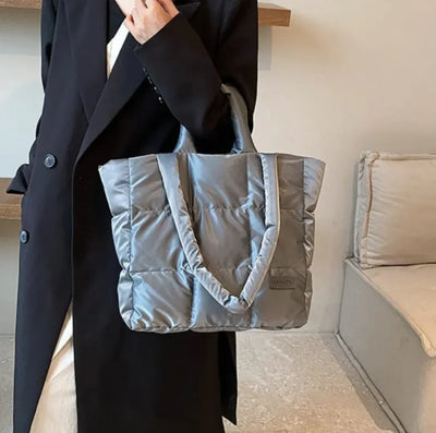 Person holding a gray puffer bag indoors