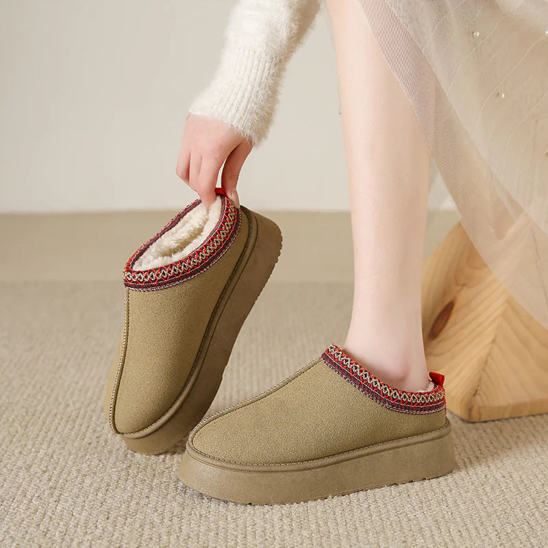 Beige slippers with red and white trim being worn indoors.