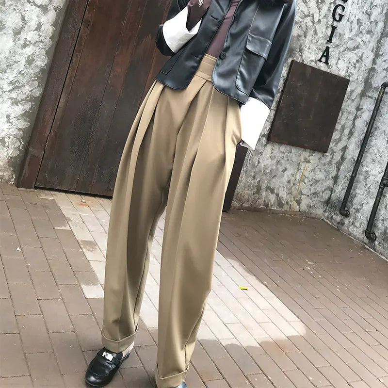 Person wearing beige wide-leg pants with a textured wall background