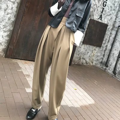 Person wearing beige wide-leg pants with a textured wall background