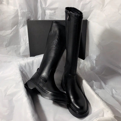 Black knee-high boots on a white fabric background
