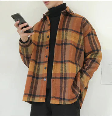 Person wearing a plaid shirt holding a phone against a white background