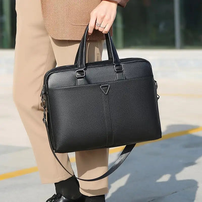 Person holding a black briefcase on a blurred outdoor background