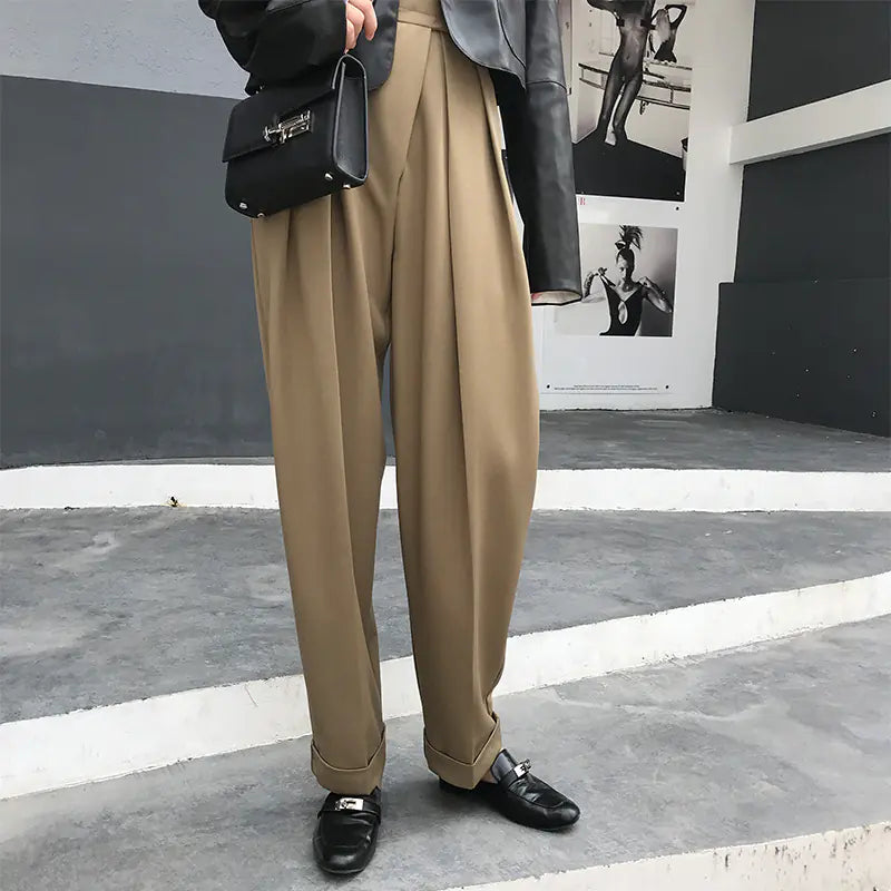 Person wearing beige pants and black shoes on a city street.
