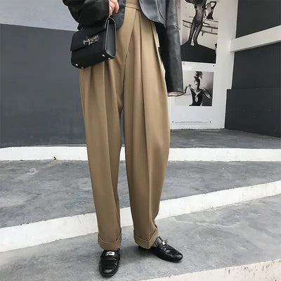 Person wearing beige pants and black shoes on a city street.