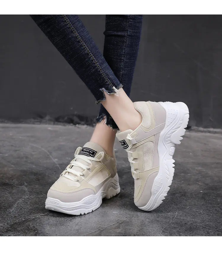 Beige sneakers with white soles worn by a person on a dark background