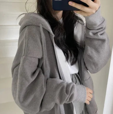 Person wearing a gray hoodie taking a mirror selfie.