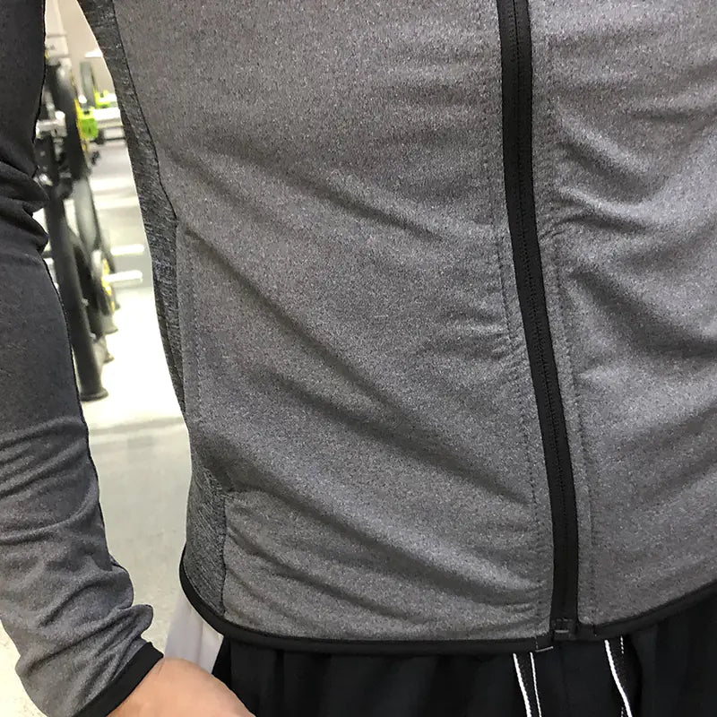 Close-up of a gray jacket with a zipper, worn by a person.