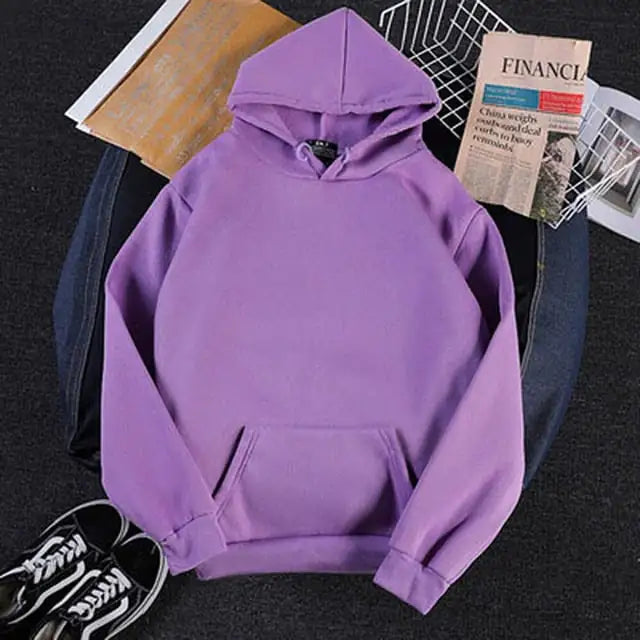 Purple hoodie on a dark surface with books and a newspaper underneath