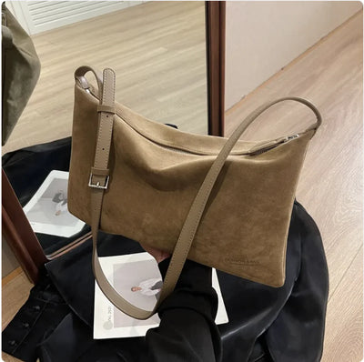 Beige handbag held by a person with a blurred indoor background