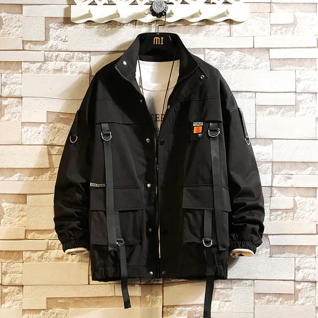Black jacket with multiple pockets and straps on a textured wall background