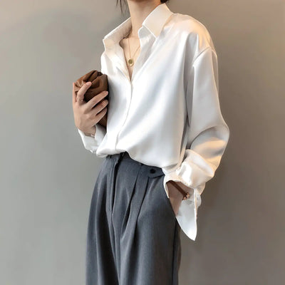 Person wearing a white shirt and gray pants against a plain background