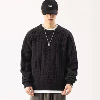 Person wearing a black cable knit sweater and cap on a white background
