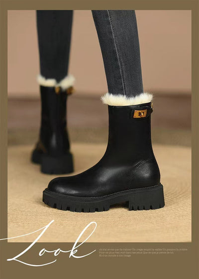 Black boots with white fur trim worn with dark jeans on a beige background