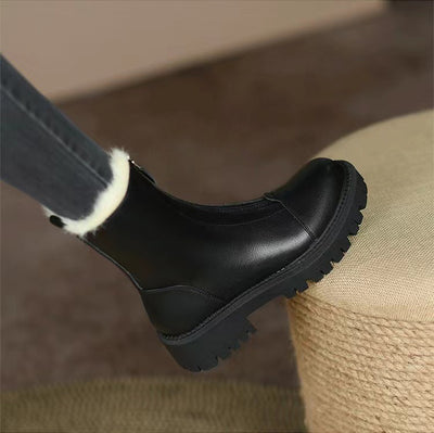 Black ankle boot with white fur lining on a blurred background