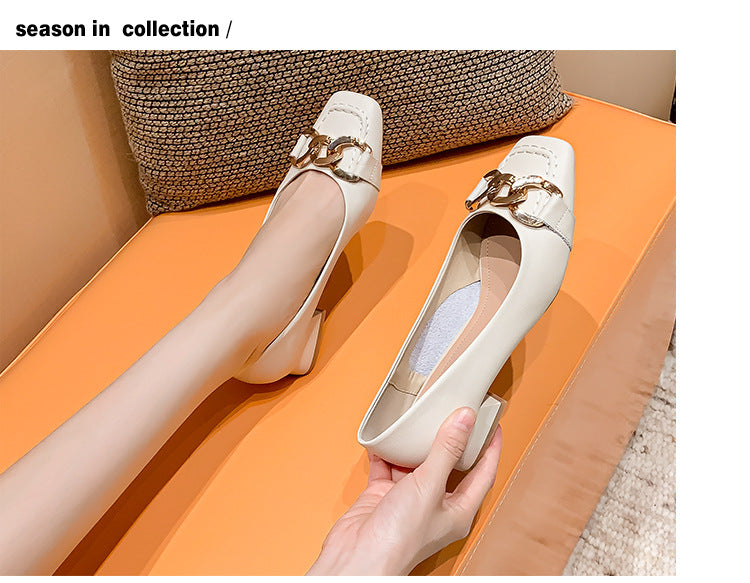 White shoes with gold buckles held by a hand on an orange surface