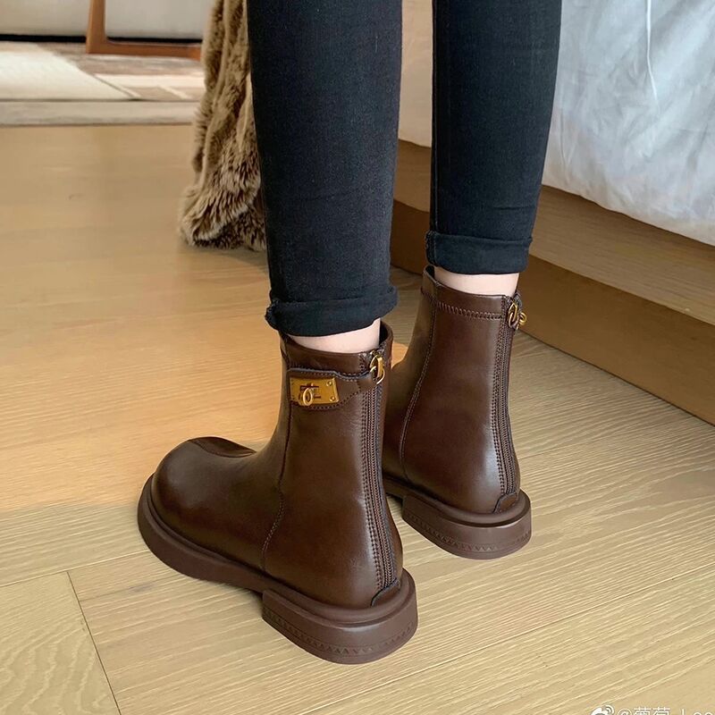 Brown leather boots worn with black pants on a wooden floor.