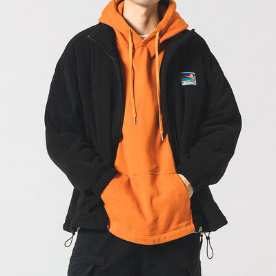 Person wearing an orange hoodie with a black jacket over it on a white background