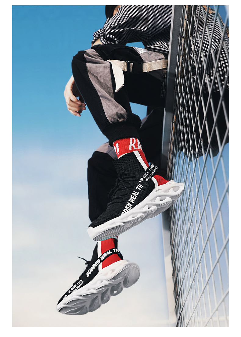 Person wearing black and red sneakers with visible branding, sitting against a blue sky.