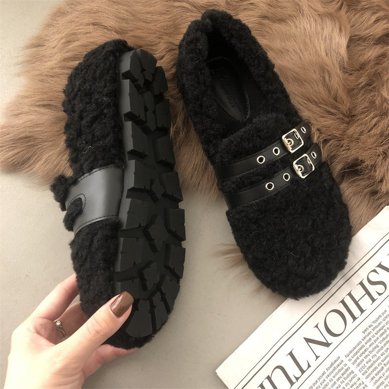 Black fuzzy slippers with buckle details on a fur surface