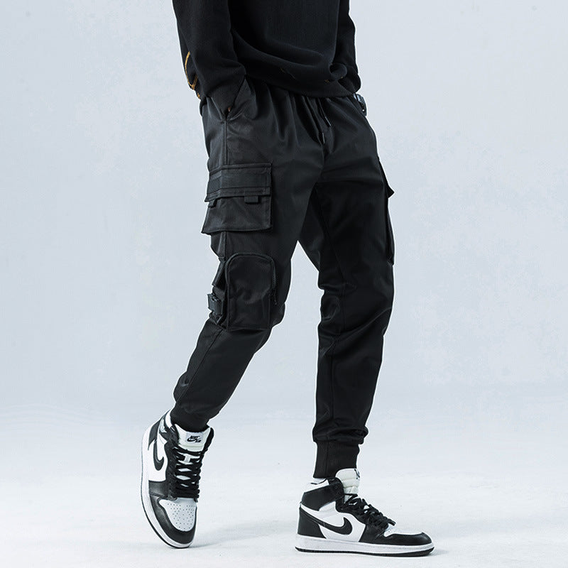 Person wearing black cargo pants and black and white sneakers on a light gray background