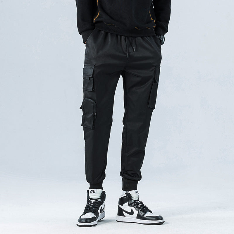 Person wearing black cargo jogger pants and black sneakers on a light gray background