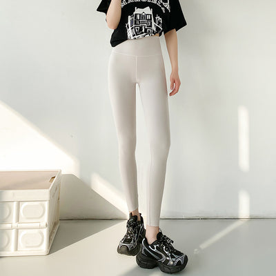 Person wearing white leggings and black sneakers in a minimalistic setting