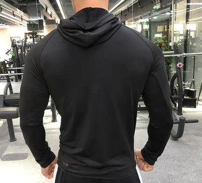 Person wearing a black hoodie in a gym setting