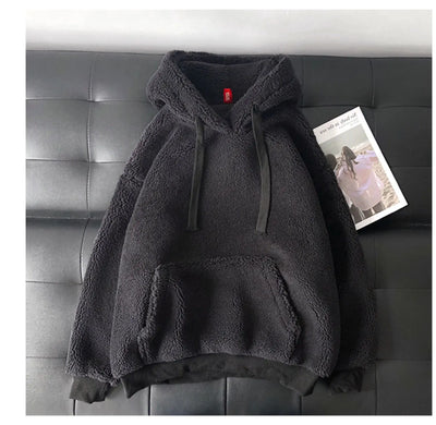 Dark gray fleece hoodie on a black leather couch with a magazine underneath.