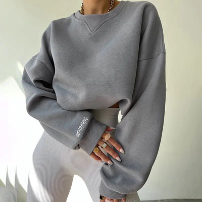 Person wearing a gray oversized sweatshirt with 'INSTUNNING' text on a light background