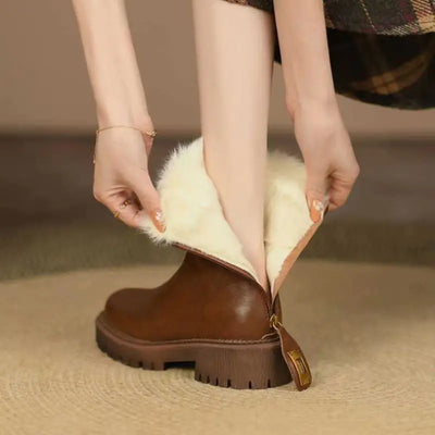 Brown leather boot with fur lining being adjusted by a person on a beige surface.