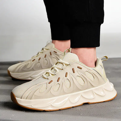 Beige sneakers worn with black pants on a gray surface
