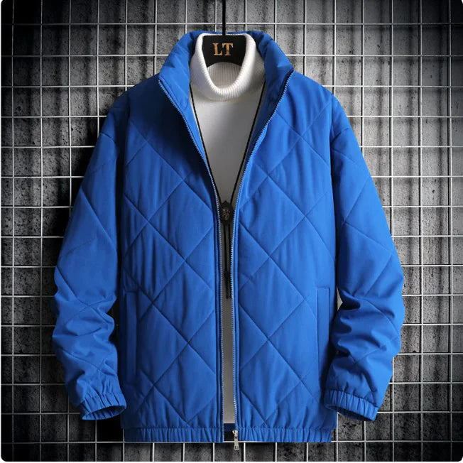 Blue quilted jacket on a hanger against a textured wall background