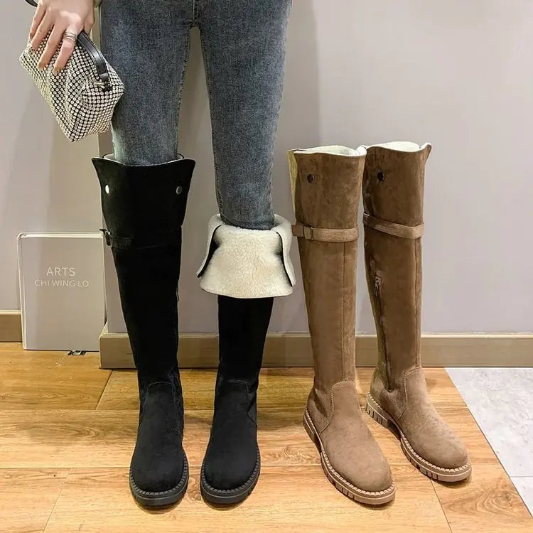 Two pairs of knee-high boots, one black and one brown, on a wooden floor.