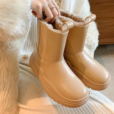 Tan rubber boots with fur lining worn by a person on a soft surface.