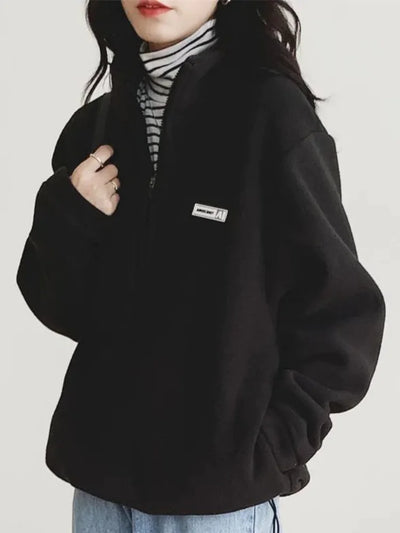 Person wearing a black fleece jacket with a brand logo on a white background