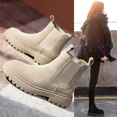 Beige Chelsea boots with a person wearing them in an urban setting.
