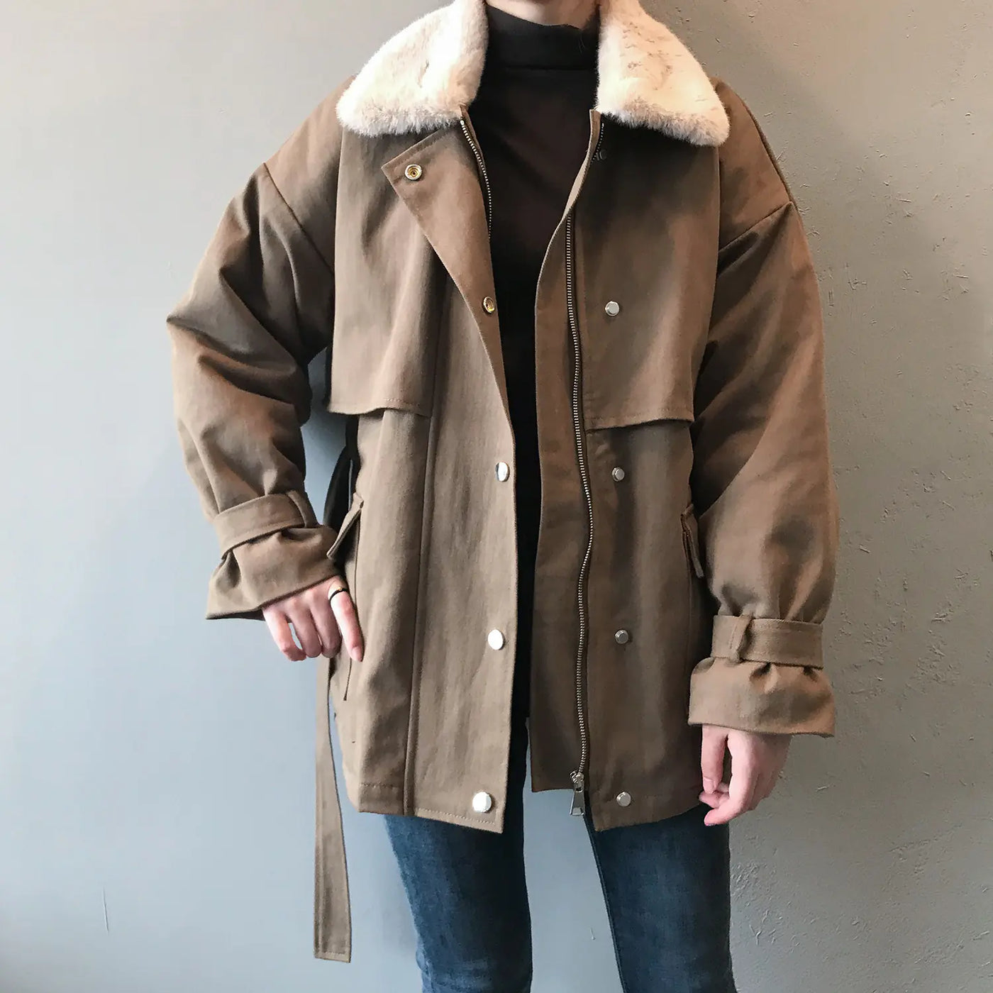 Brown coat with fur collar worn by a person against a plain background